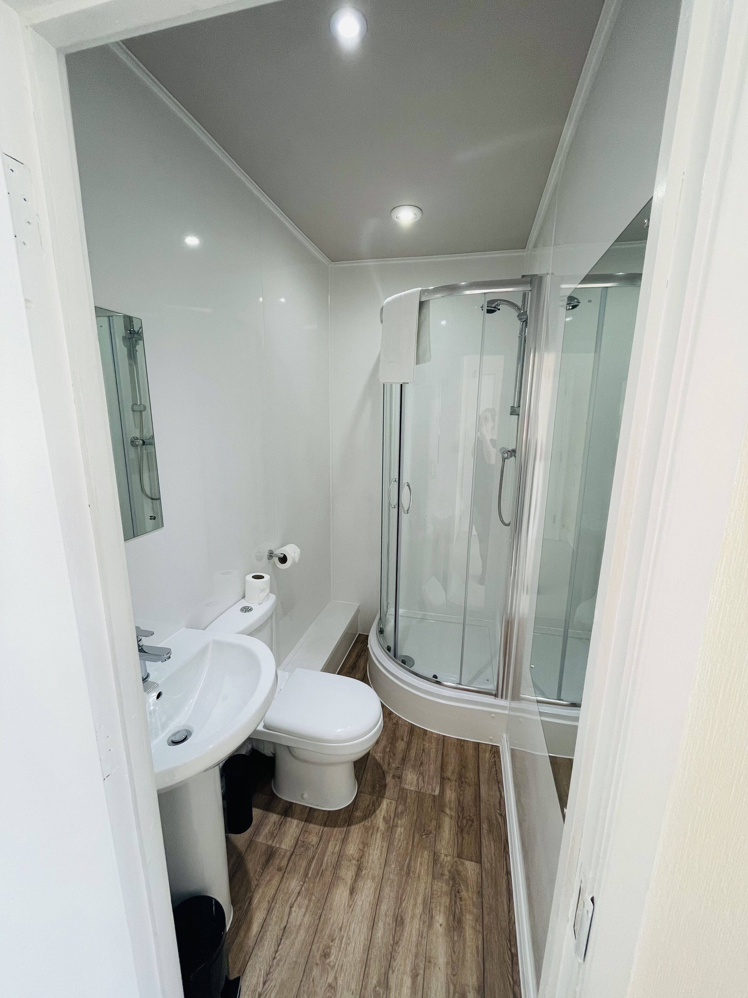 A modern bathroom with a glass shower enclosure, a white sink, and a toilet.