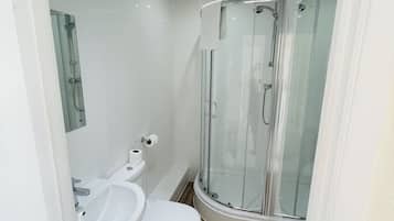 A modern bathroom with a glass shower enclosure, a white sink, and a toilet.