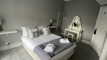 A bedroom with a large bed, bedside tables, a mirror, and a hanging light fixture.