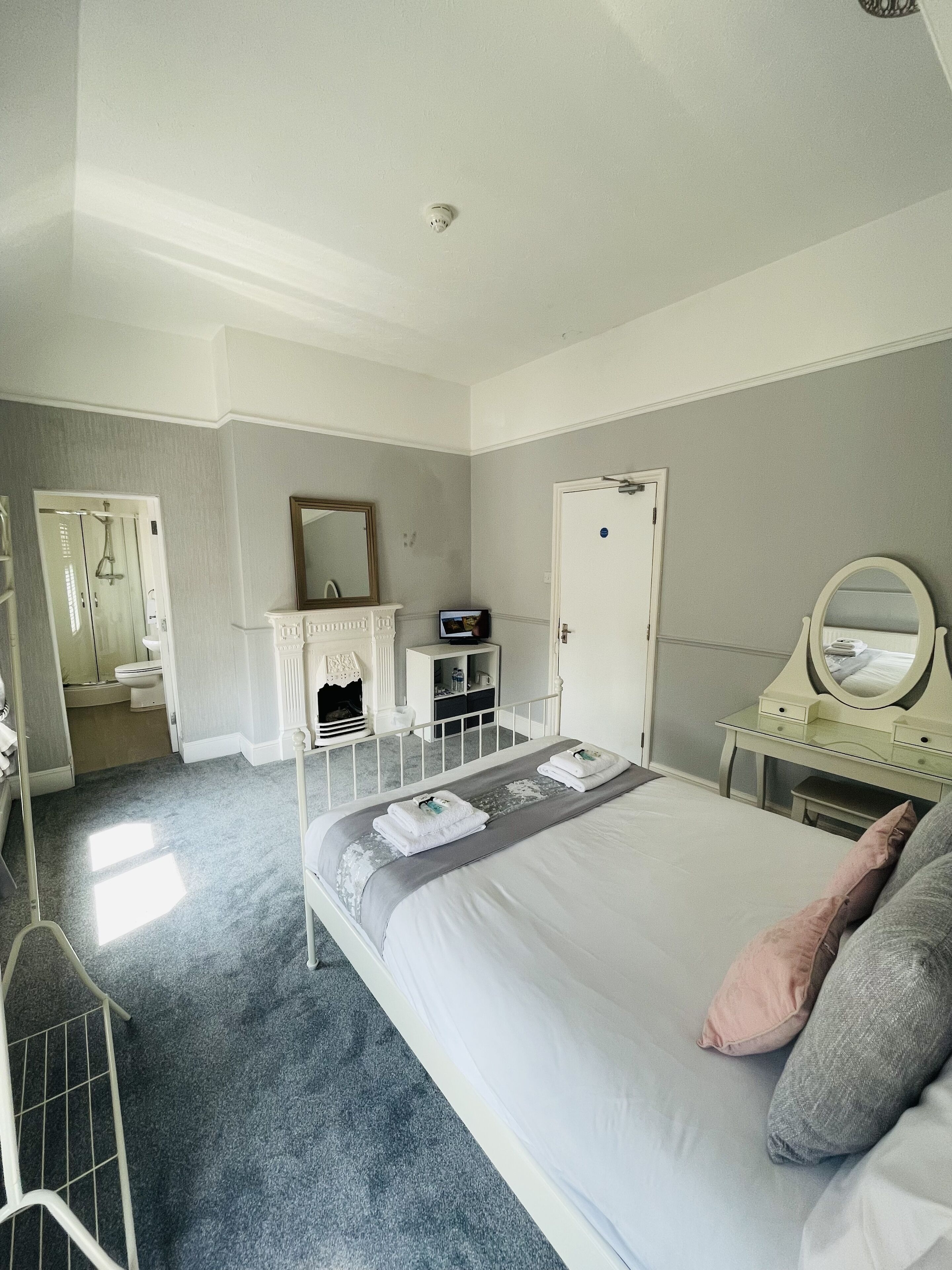 Ein Schlafzimmer mit einem Bett, einem Schminktisch, einem Spiegel und einer Tür.