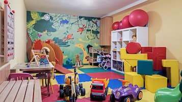 Children can play and explore in this vibrant playroom featuring a play mat, slide, and toy truck.