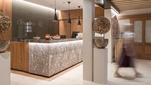 Una zona de recepción moderna con mostrador de mármol, detalles de madera e iluminación colgante.