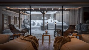 Un espacio interior acogedor con vistas a un paisaje nevado, paredes de madera y un sillón colgante.