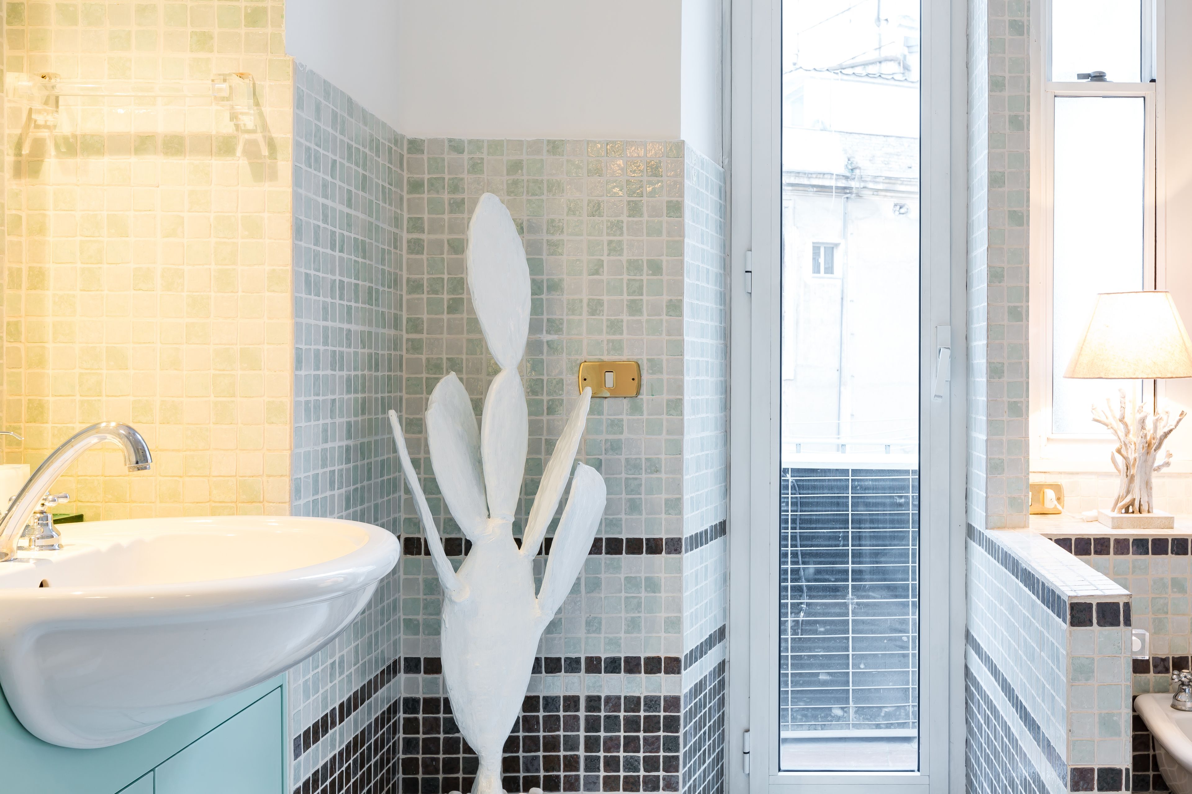 A bathroom with a sink, a white vase, and a window with blinds.