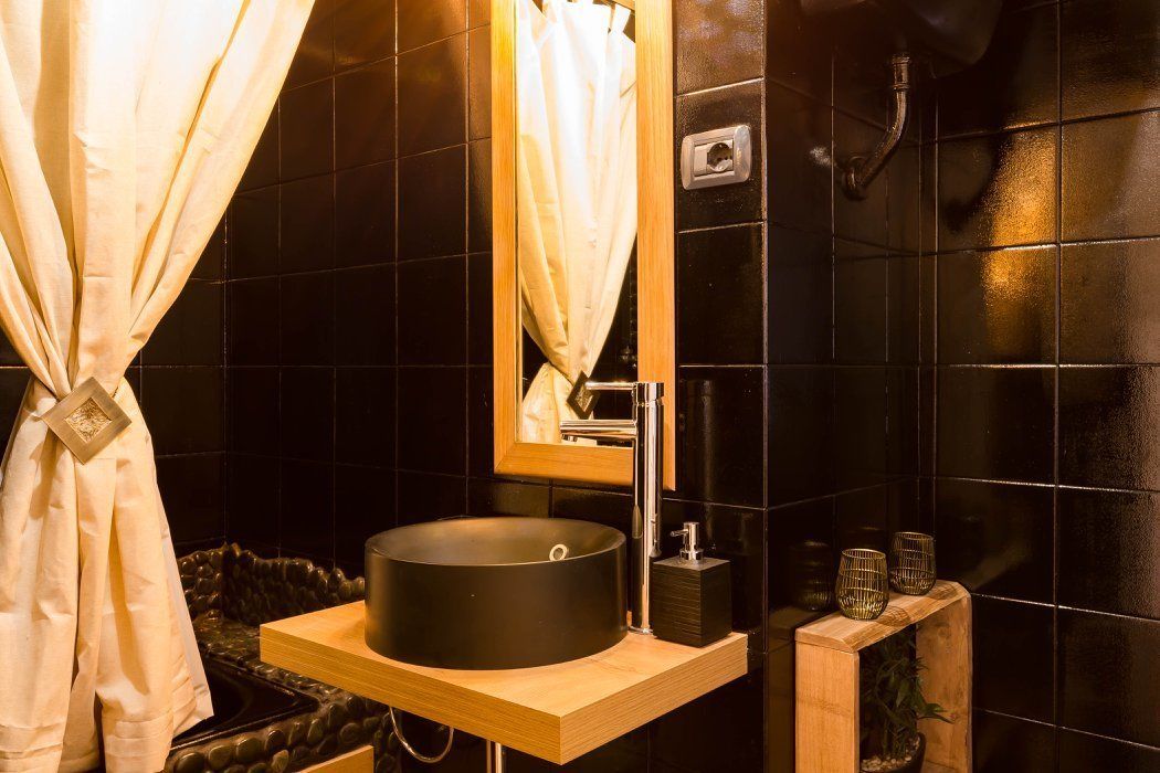 A bathroom with a round sink, a mirror, and a shower area.