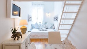 Un dormitorio con una cama, una mesita de noche, una lámpara, una pequeña figurita de elefante y una escalera.