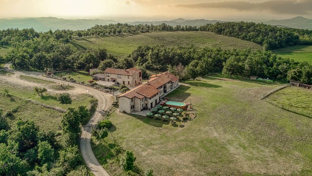 A large estate with a main building, multiple outdoor seating areas, and a swimming pool.