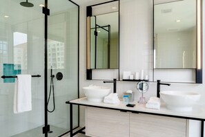 A modern bathroom with a glass-enclosed shower, two sinks, a large mirror, and a towel rack. - Hyde Suites Midtown Miami (Miami)