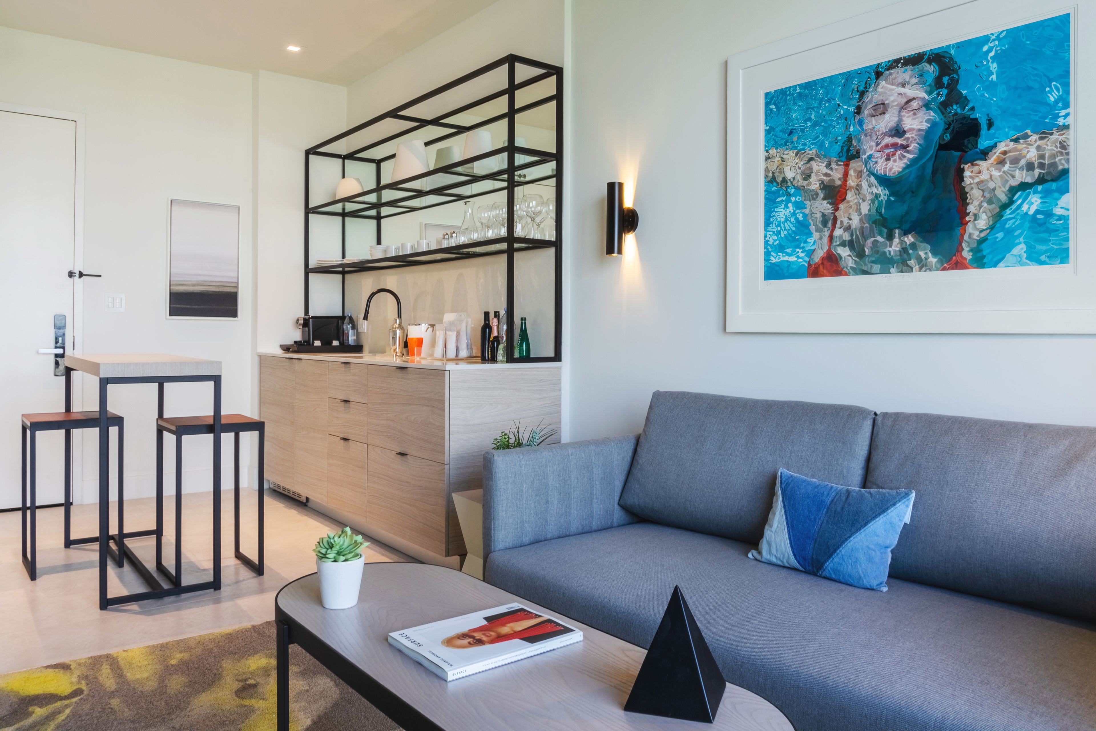 A modern living room with a grey sofa, a coffee table, and a bookshelf.