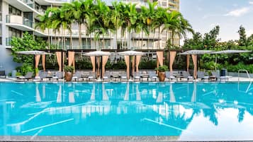 Relax by the pool surrounded by lounge chairs and umbrellas, with a clear view of the surrounding area.
