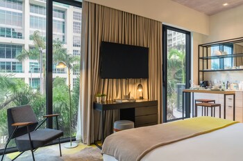 A multi-story hotel with balconies, a central courtyard with palm trees, and a street view. at Hyde Suites Midtown Miami