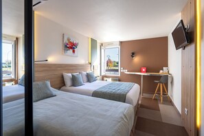 Et hotelværelse med to senge, et skrivebord, et fjernsyn og et vindue med udsigt.
