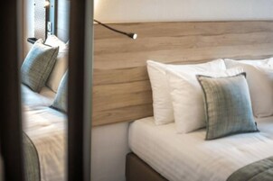 Cama bem arrumada com cabeceira de madeira e dois travesseiros.