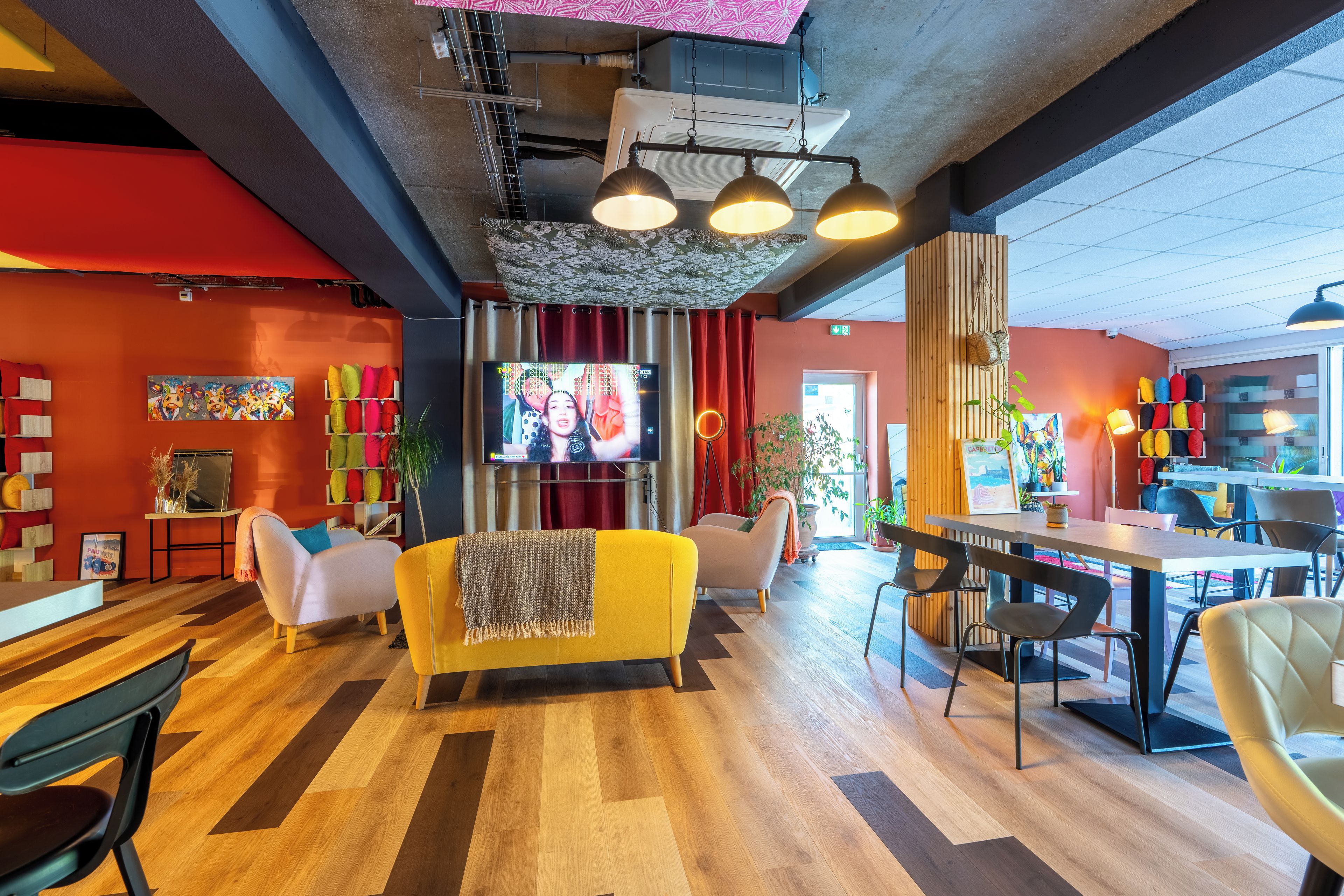Un intérieur moderne avec un plancher en bois, un canapé jaune, un téléviseur et un coin repas.
