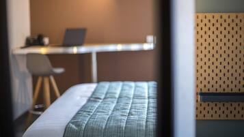 Una habitación de hotel con una cama, un escritorio con una computadora portátil y una silla.