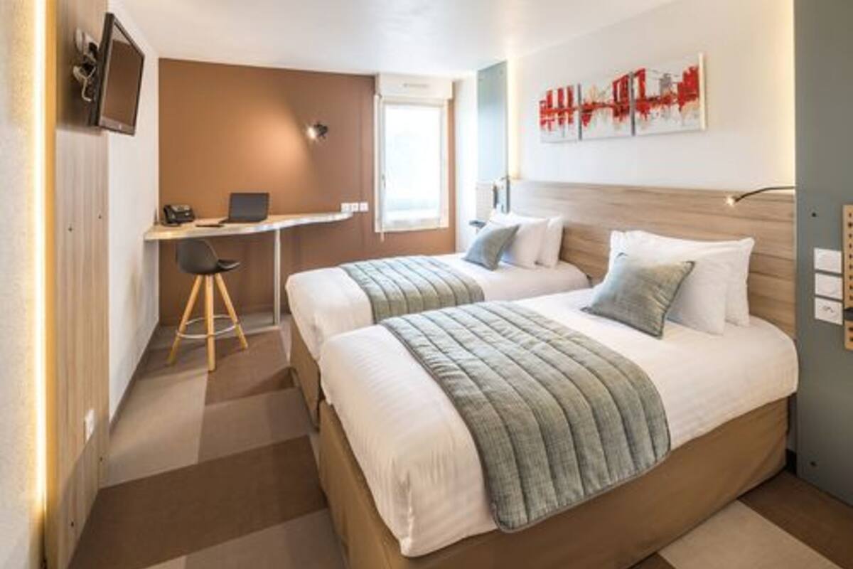 A hotel room with two beds, a desk, and a chair.