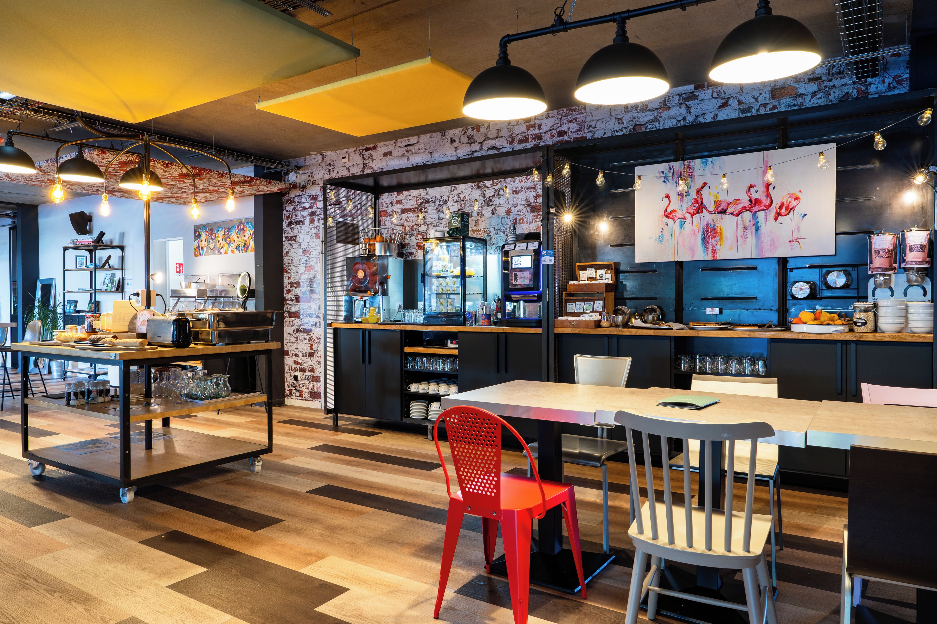 A modern cafe interior with a bar area, seating, and a mural on the wall.