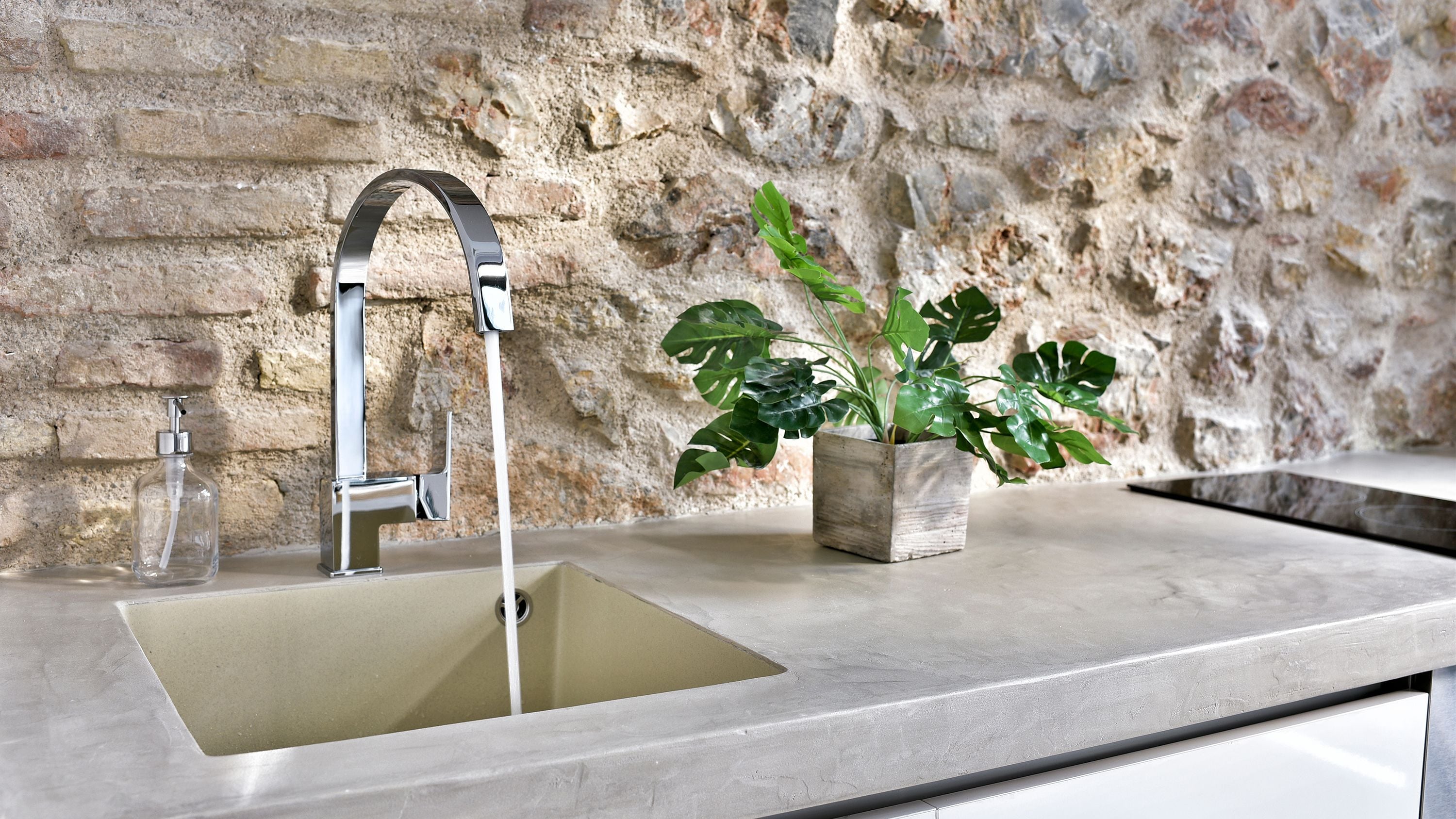 Una cocina moderna con un lavamanos de acero inoxidable, un grifo y una planta en maceta.