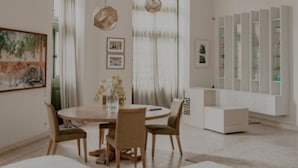 Una sala de estar moderna con una mesa de comedor redonda, asientos cómodos, una mesa de centro y una estantería empotrada.