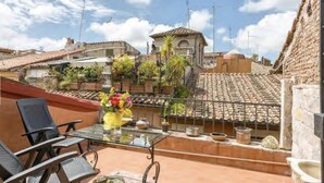 Une terrasse sur le toit, avec une table et des chaises, entourée de plantes en pot et offrant une vue sur le paysage urbain.