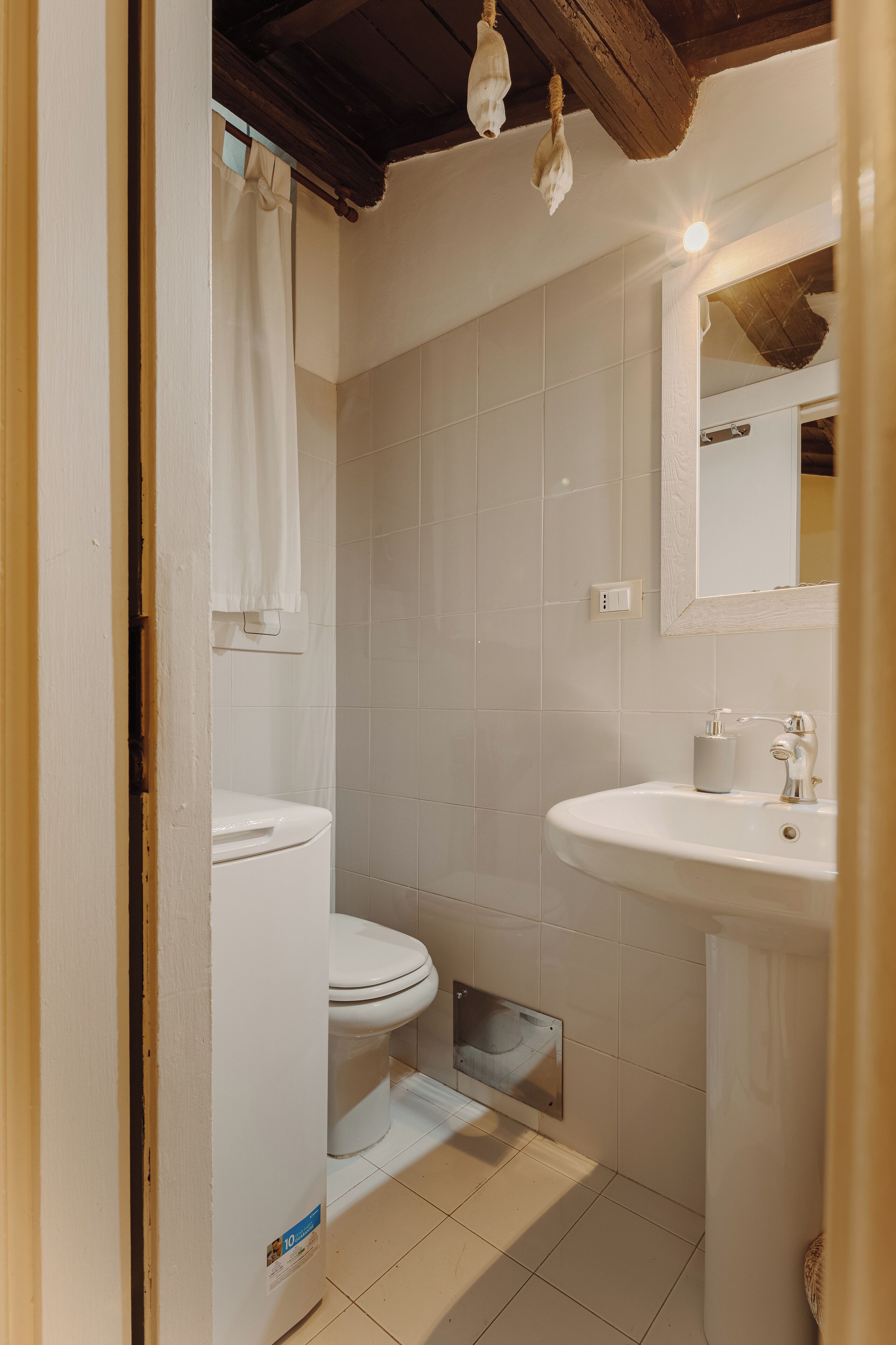 Une petite salle de bain propre, équipée de toilettes, d’un lavabo et d’un miroir.