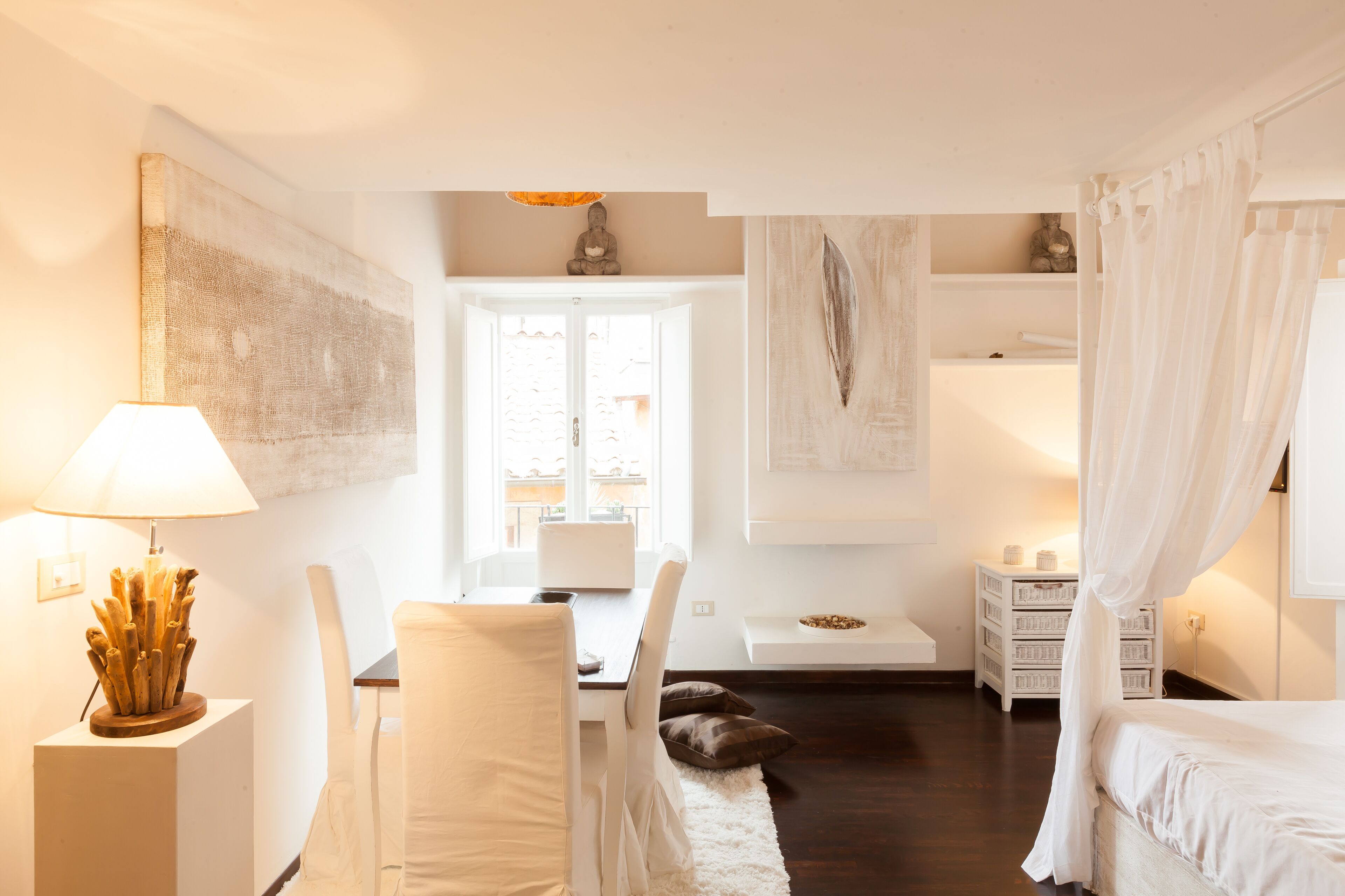 A modern bedroom with a bed, bedside table, lamp, and a view of the outside.