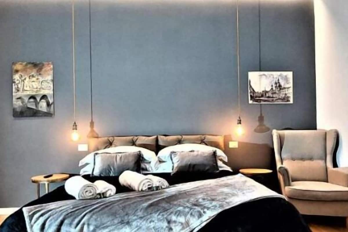 Una camera da letto con un letto, una sedia e due lampade a parete.
