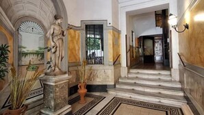 A grand hallway with marble flooring, a statue, and a staircase leading to another area. - Vatican Rome Suite (Rome)