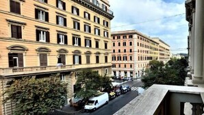 A street view with multi-story buildings, a white van parked on the side, and a pedestrian crossing. - Vatican Rome Suite (Rome)