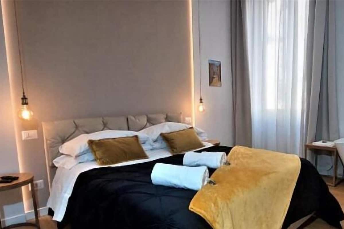 Una camera da letto moderna con un letto, comodini, un tavolino da notte e una vasca da bagno.