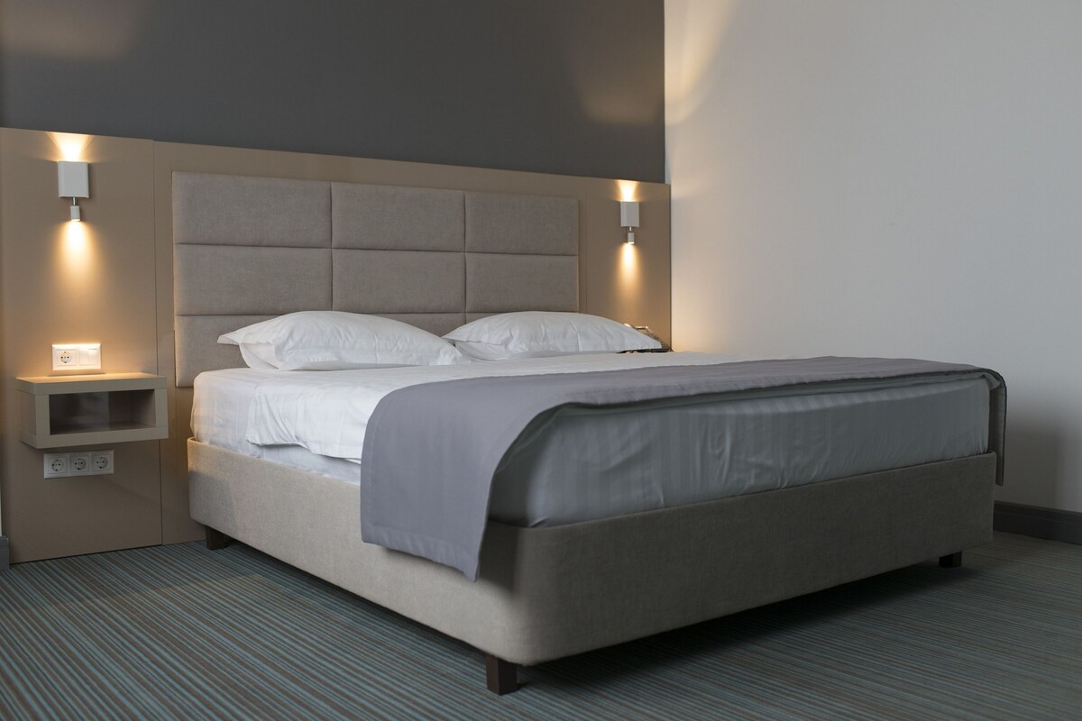 Una habitación de hotel moderna con una cama grande, dos mesitas de noche y apliques de pared.