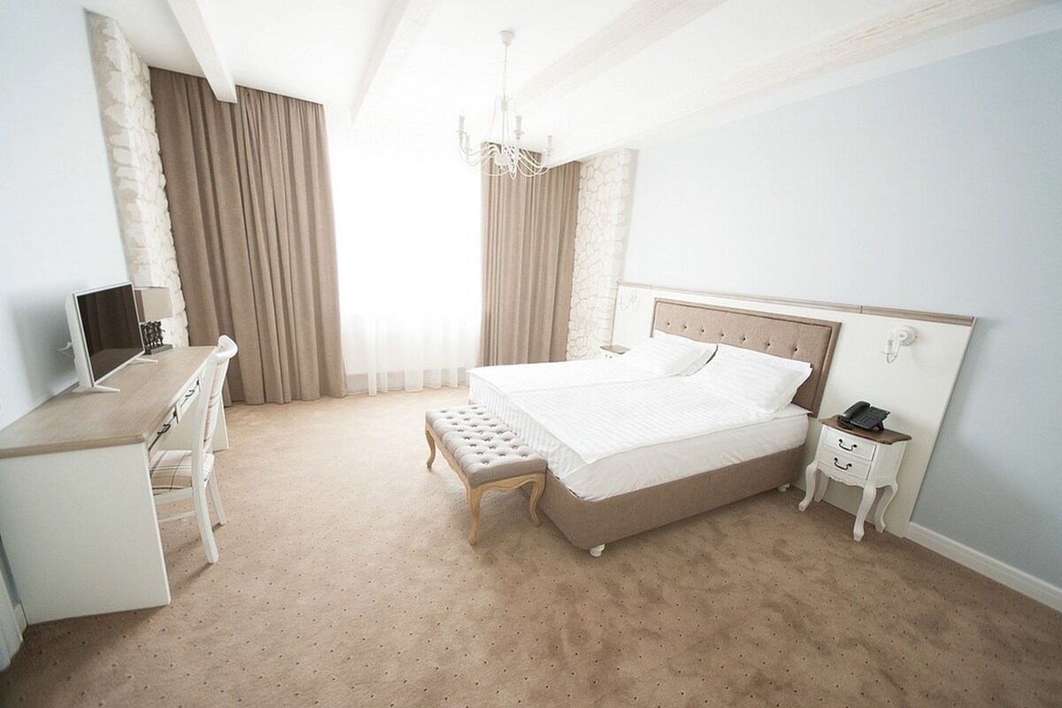 Un dormitorio con cama, mesita de noche, lámpara y escritorio con silla.