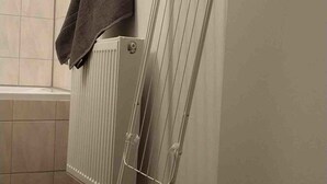 Ein Badezimmer mit weißem Heizkörper, einem Handtuchhalter mit Handtuch und einer Tür mit Griff.