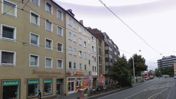 A street with multi-story buildings, shops, and a tram line.