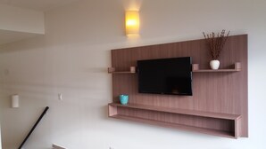 A wall-mounted TV with wooden shelves and a small vase with dried branches. - Bariloche Downtown 3 II (San Carlos de Bariloche)