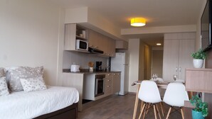 A compact bedroom with a bed, a small kitchenette, and a dining area with chairs and a table. - Bariloche Downtown 3 II (San Carlos de Bariloche)