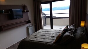 A bedroom with a bed, a television, a radiator, a balcony with a view of mountains, and a lamp. - Bariloche Downtown 3 II (San Carlos de Bariloche)