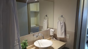 A modern bathroom with a large mirror, a sink, and two towels hanging on hooks.