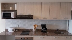A compact kitchen with a microwave, toaster, coffee maker, and a sink. - Bariloche Downtown 3 II (San Carlos de Bariloche)