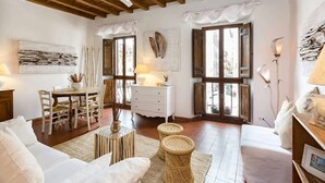 Una sala de estar acogedora con techo de madera, un sofá blanco, una mesa de comedor con sillas y un aparador blanco.