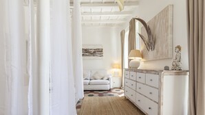 A hallway with a white sofa, a wooden dresser, and a lamp. - Campo Home (Rome)