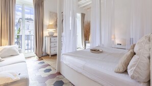 A bedroom with a large bed, a bedside table, a lamp, and a view of the outside. - Campo Home (Rome)