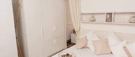 Un dormitorio con cama, armario blanco y estante con adornos.