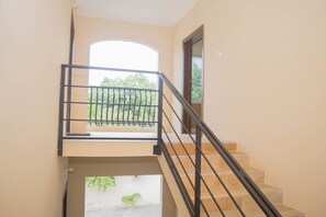 Stairs lead to an upper level with a door and a view of the surrounding greenery.