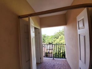 Un couloir menant à un balcon d’où l’on peut admirer un paysage verdoyant.