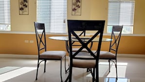 En matplats med ett runt bord i glas och fyra stolar, två på varje sida.