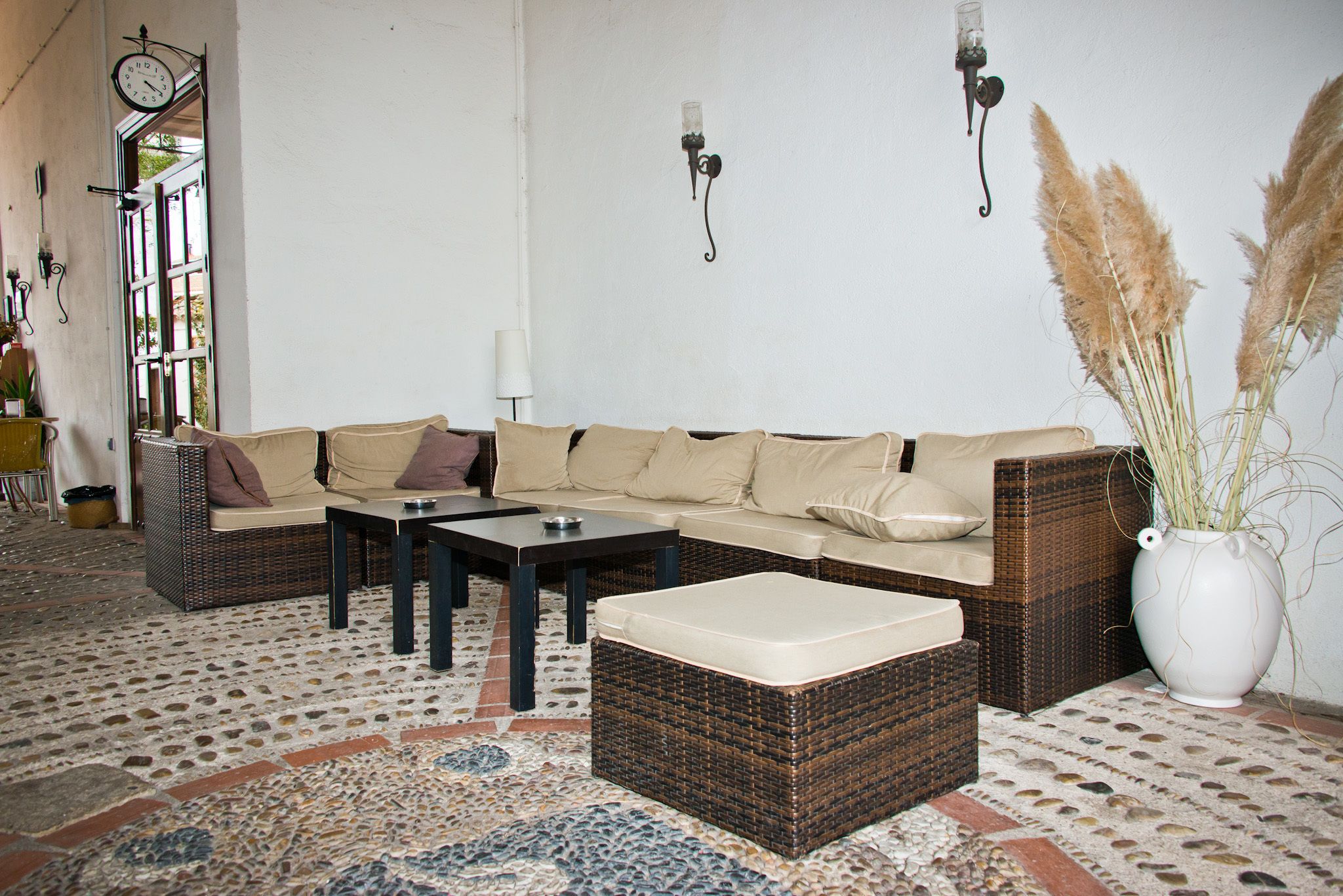 Un salon chaleureux avec un canapé en osier, un pouf assorti et un tapis à motifs.