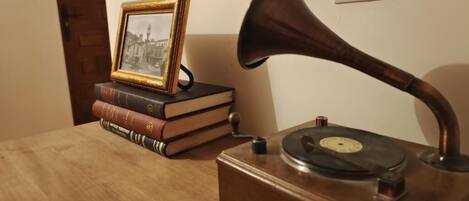 Un tocadiscos sobre una mesa de madera con libros y un cuadro enmarcado a su lado.