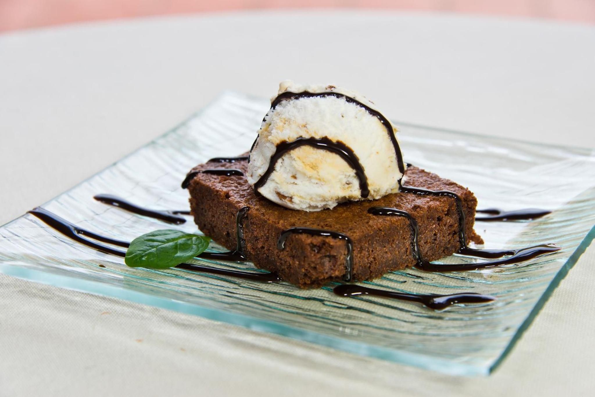 A dessert on a glass plate with chocolate sauce and a mint leaf garnish.