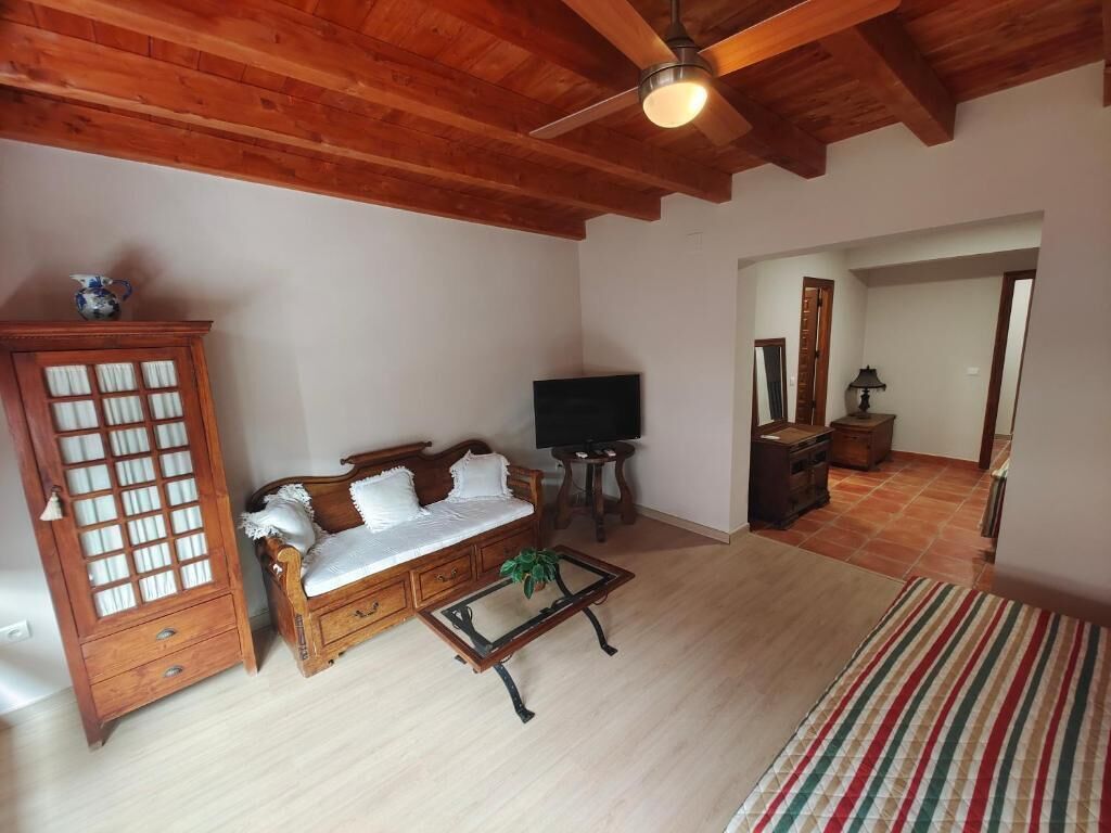 Una sala de estar con techo de madera, un sofá, un televisor, un armario y una alfombra a rayas.